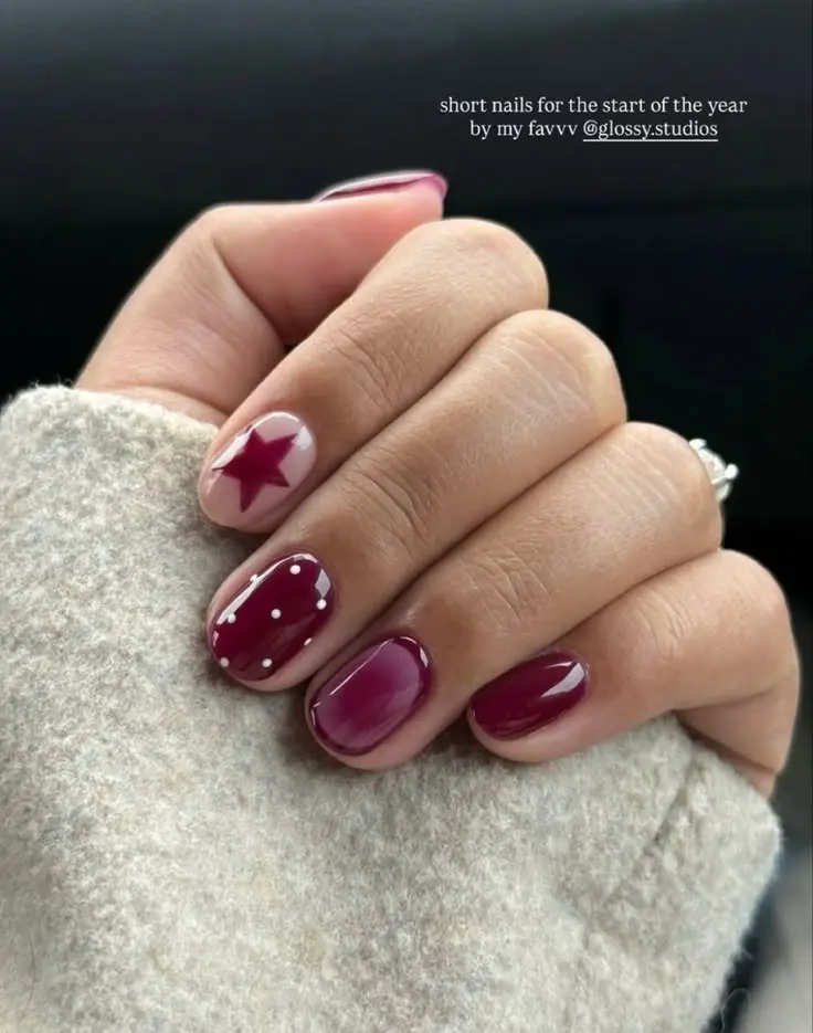 short round nails deep cranberry burgundy gel with one sheer blush accent star nail and one nail with scattered white pearl dots photo 8