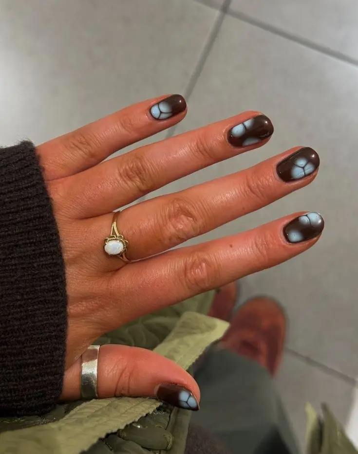 short round nails dark oxblood brown gel base with abstract powder blue crackle floral shapes on each nail high gloss finish photo 19