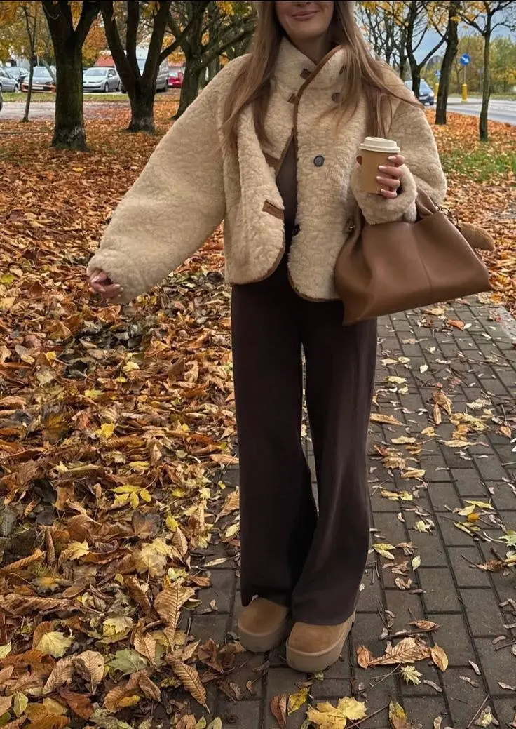 woman walking in caramel teddy shearling coat chocolate brown wide leg trousers platform UGG boots cognac leather shoulder bag autumn leaves pumpkin patch outfit 5