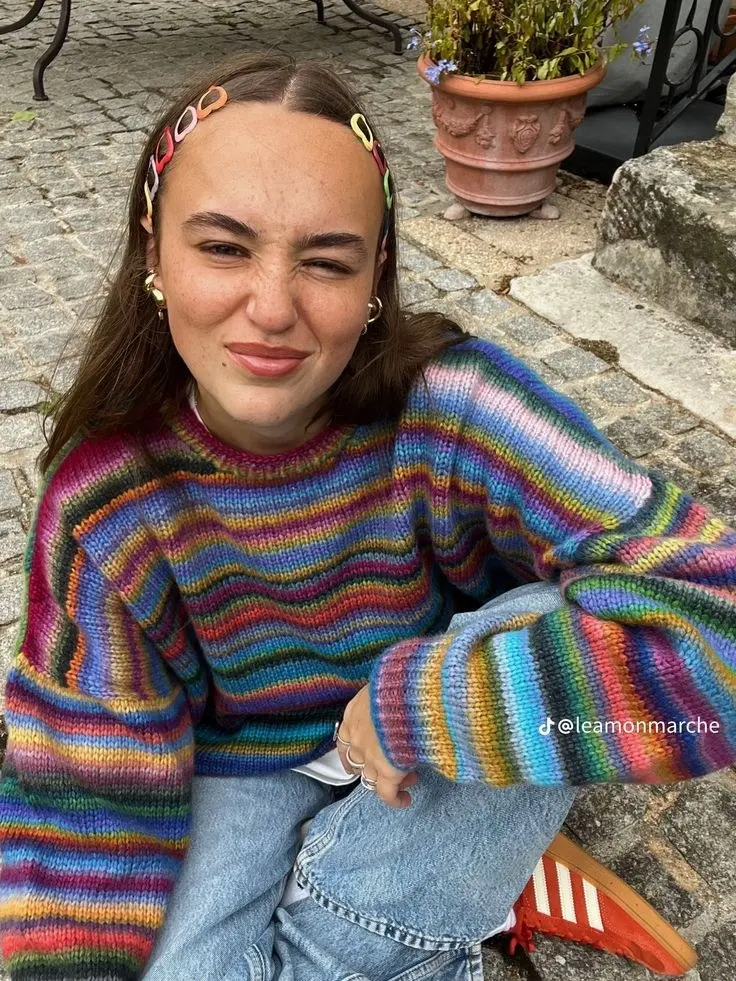 close up woman in chunky rainbow striped crew neck sweater colorful headband gold hoop earrings light wash jeans red white sneakers pumpkin patch outfit 14