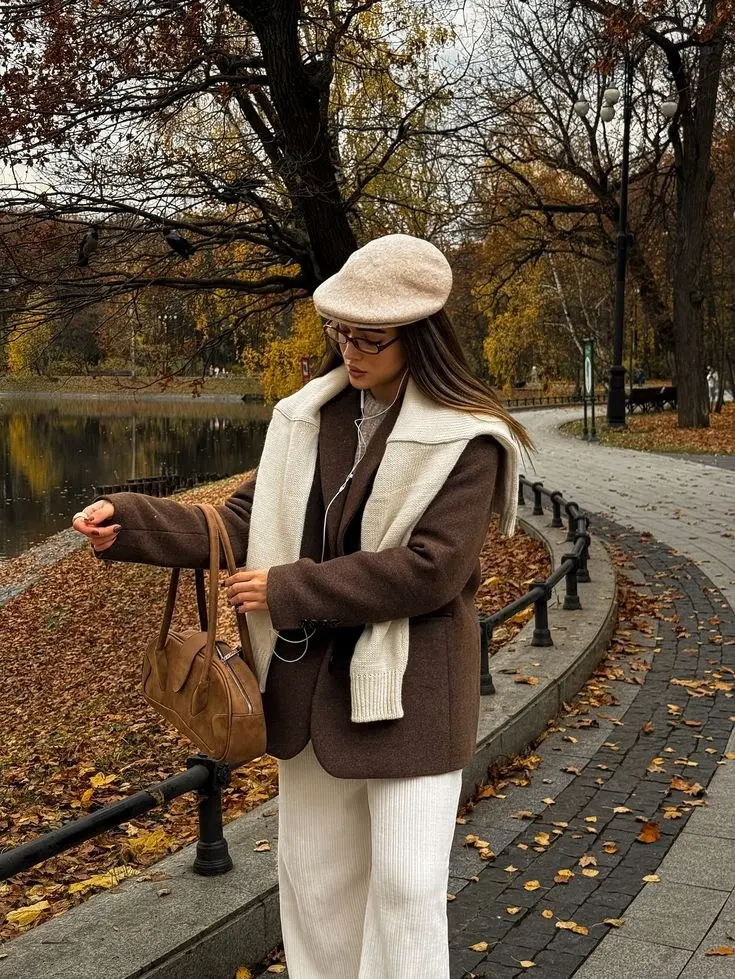woman walking in autumn park in chocolate brown blazer cream oversized knit turtleneck layered cream ribbed wide leg trousers tan suede shoulder bag camel wool beret glasses pumpkin patch outfit 19