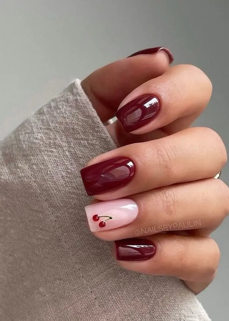 short square nails in glossy deep burgundy with one blush pink accent nail featuring small painted red cherry with green stem, photo 4