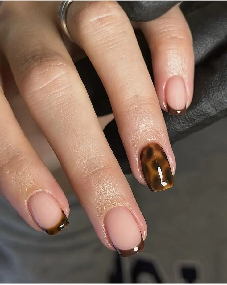 short square nails with sheer nude base, tortoiseshell French tips on two fingers, one fully solid tortoiseshell accent nail, close-up detail, photo 5