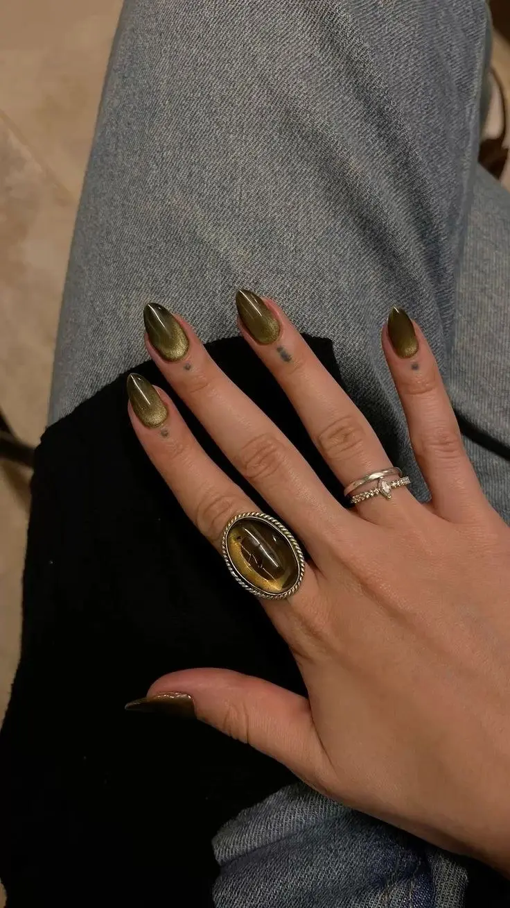 almond nails in deep olive khaki chrome cat eye finish with gold-green duochrome shift, worn with silver rings, photo 4