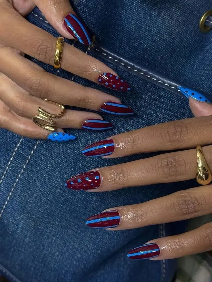 long almond nails with vertical burgundy and cobalt blue stripes on most nails, solid blue nail with burgundy dots and solid burgundy nail with blue dots as accents, photo 12