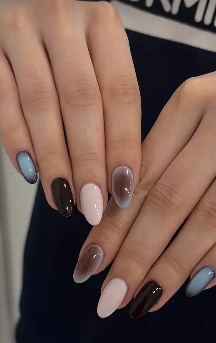 medium almond nails in multi-tonal gradient across the full hand from pale blush white through powder blue taupe grey and deep espresso, each nail a different solid color, high gloss, photo 13