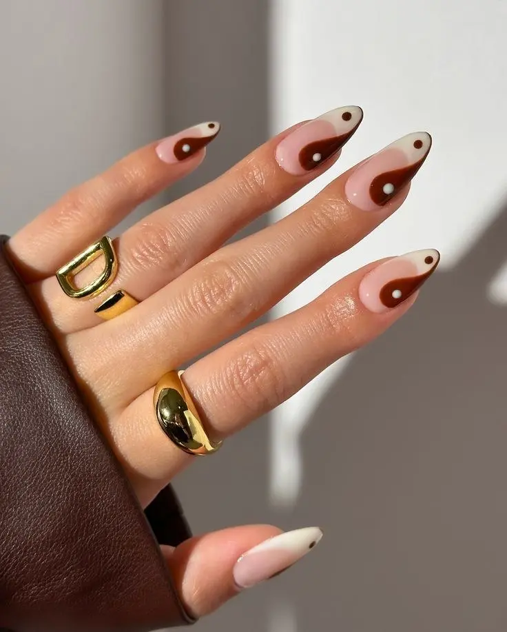 medium almond nails with sheer nude base and terracotta brown and cream yin-yang symbol design on each nail, gold chunky rings, photo 16