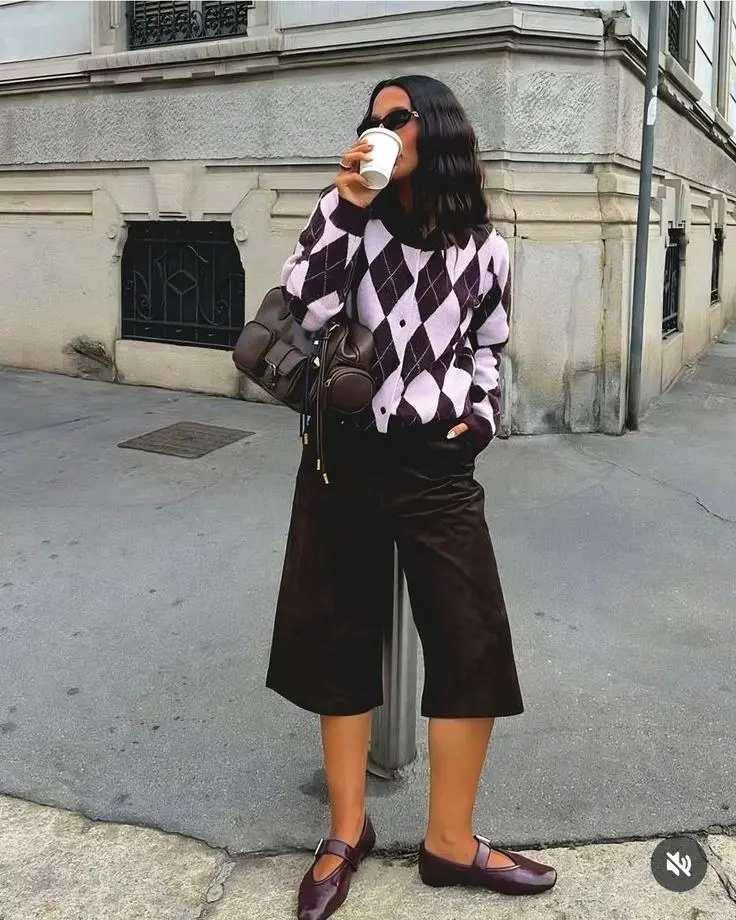 woman in lavender purple argyle oversized cardigan dark plum velvet culottes dark plum mary jane ballet flats small dark leather structured bag sunglasses street style outfit 15