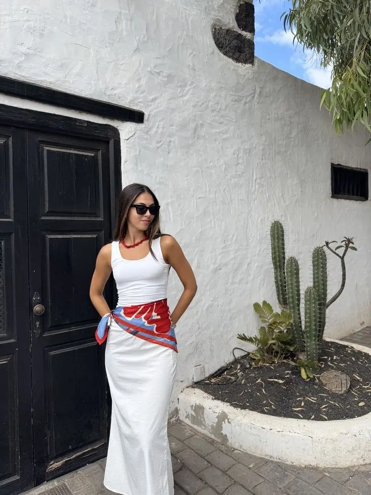 woman in white fitted tank white linen maxi skirt red blue printed silk scarf as belt red beaded choker sunglasses standing against white adobe wall with cactus outfit 10