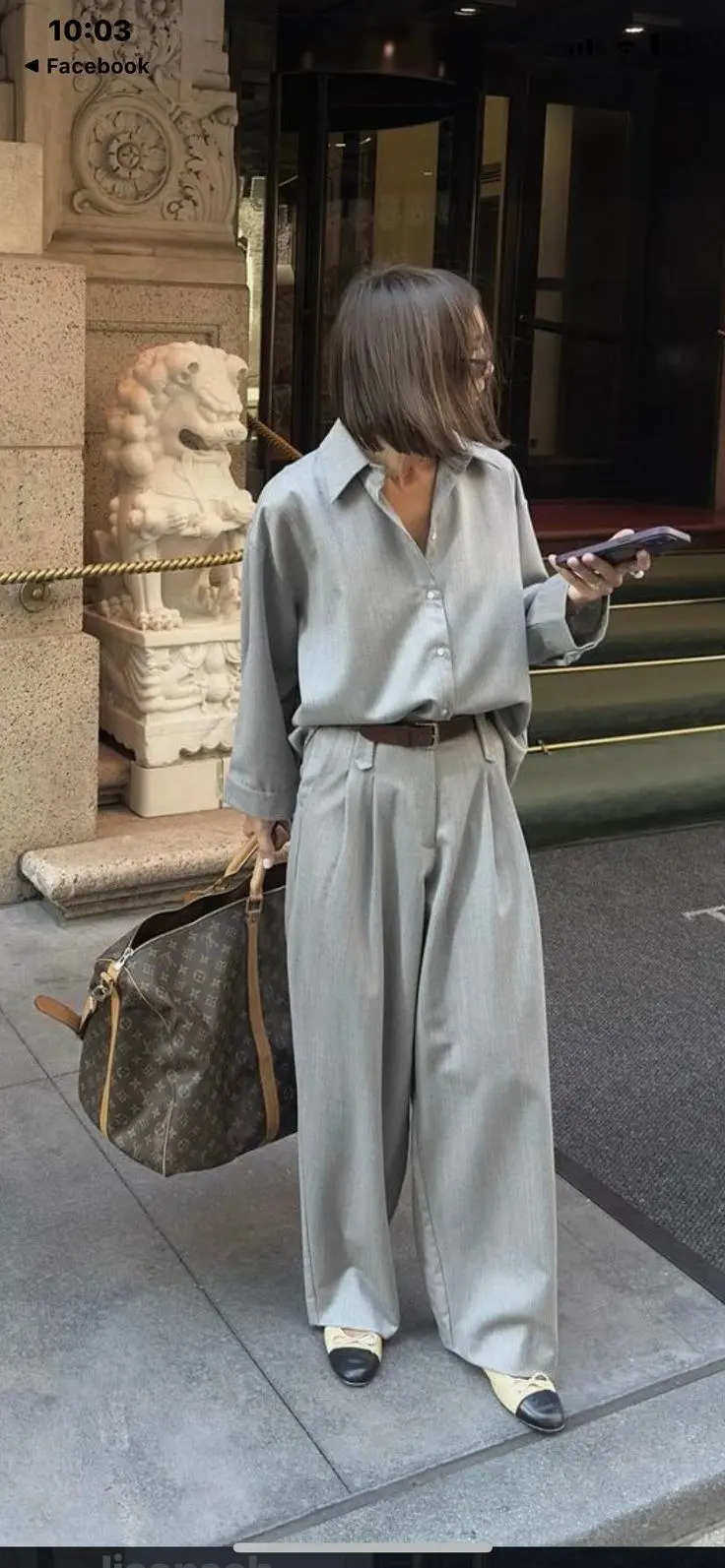 Woman in head-to-toe charcoal gray oversized blazer and matching wide-leg trousers, walking cobblestone Paris street, autumn light, fashion week energy