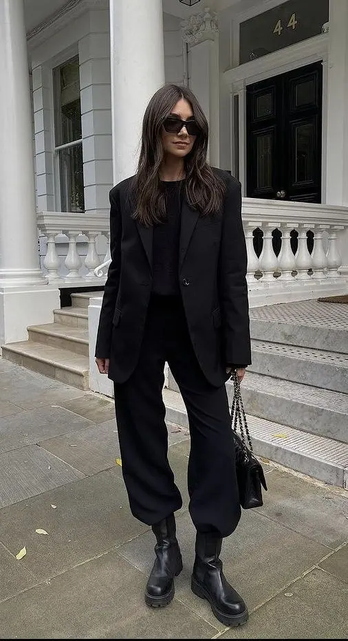 Over-the-knee black leather boots styled under a midi wrap skirt and oversized blazer, fashion week street style New York fall