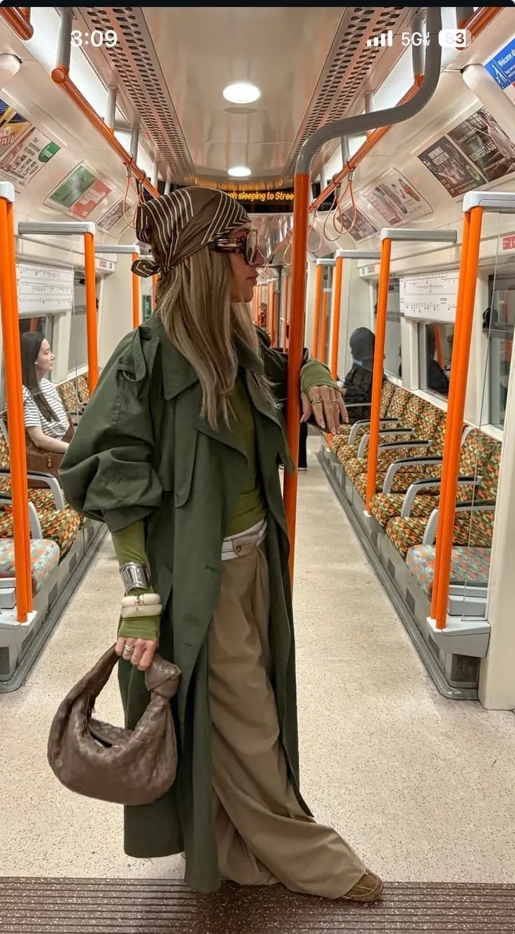 Cargo pants in deep forest green, layered under a long trench coat with white sneakers peeking out, editorial proportion