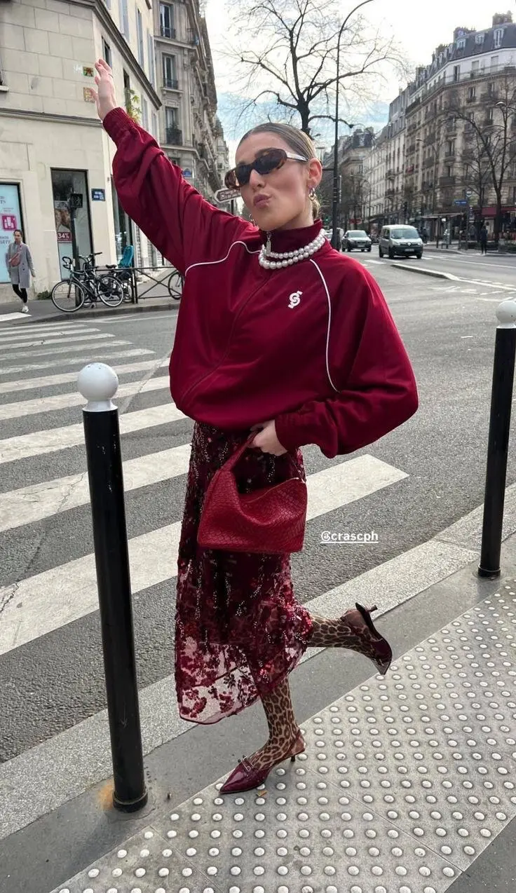 Tomato red leather jacket over cream knit and dark jeans, bold fall color dressing, city sidewalk photography