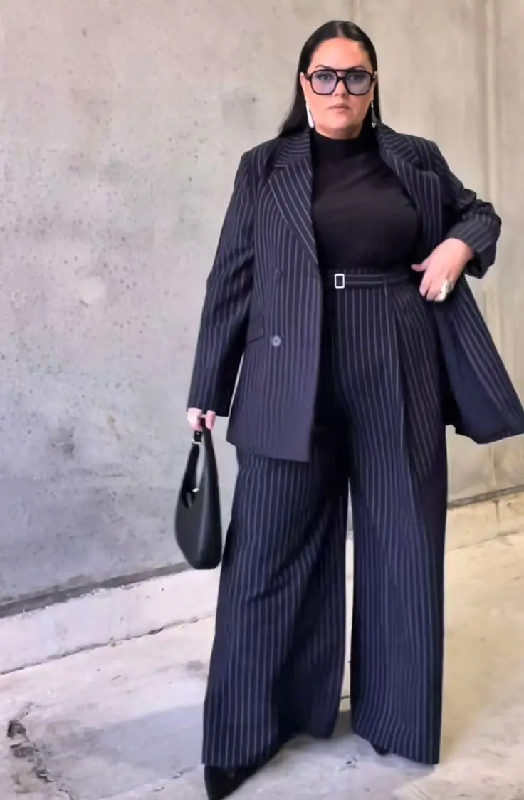 Curvy woman in deep sapphire longline blazer, wide-leg black trousers, pointed-toe heels, office setting