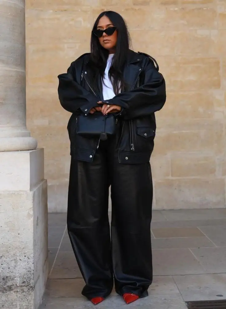 Plus size model in chocolate brown leather midi dress, minimal jewelry, knee-high boots, editorial soft lighting