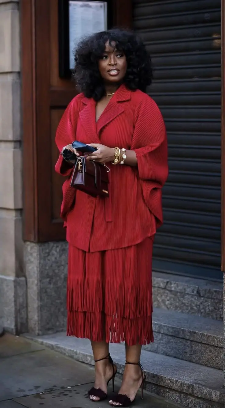 Curvy fashion blogger in ruby red tailored blazer and matching trousers, gold accessories, bold confident pose