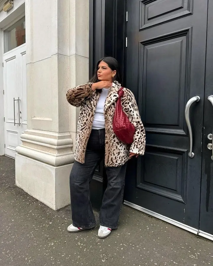 Curvy woman in classic leopard print longline coat over all-black outfit, ankle boots, city street fall setting