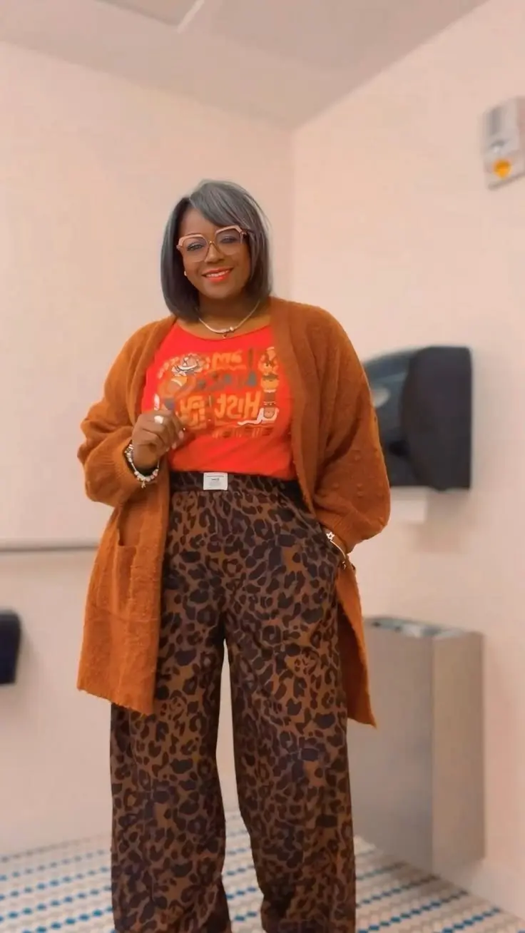 Plus size woman in snakeskin effect midi skirt, black ribbed knit, block heel boots, warm indoor cafe setting