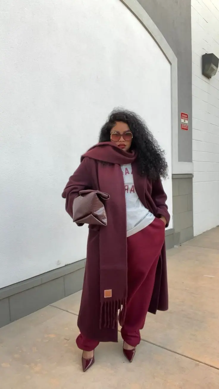 Curvy woman in camel longline belted wool coat over dark tonal outfit, knee-high boots, autumn city street
