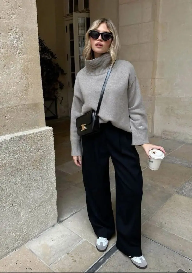 woman wearing oatmeal turtleneck oversized sweater wide-leg black trousers white Adidas Samba sneakers black Celine crossbody bag cat-eye sunglasses coffee cup outdoor street outfit 6
