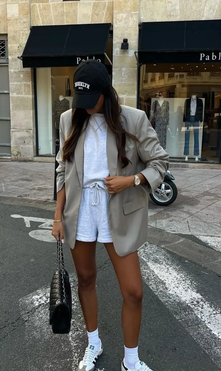woman wearing black NY cap oversized khaki blazer grey sweat shorts grey sweat top white Adidas sneakers white ankle socks black quilted chain bag street outfit 10
