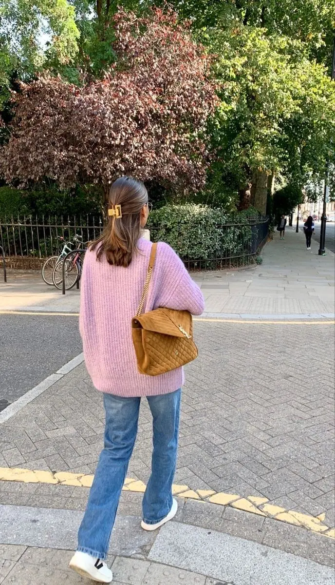 woman from behind in lavender oversized knit sweater blue straight jeans gold hair clip caramel quilted shoulder bag and white Veja sneakers outdoor street outfit 9