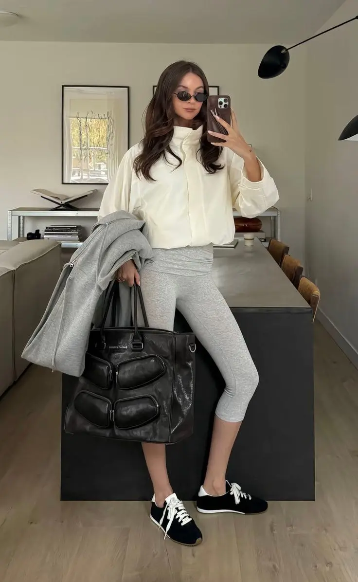 woman mirror selfie in cream zip puffer jacket grey leggings black Alo sneakers grey hoodie carried over arm large black tote bag sunglasses outfit 6