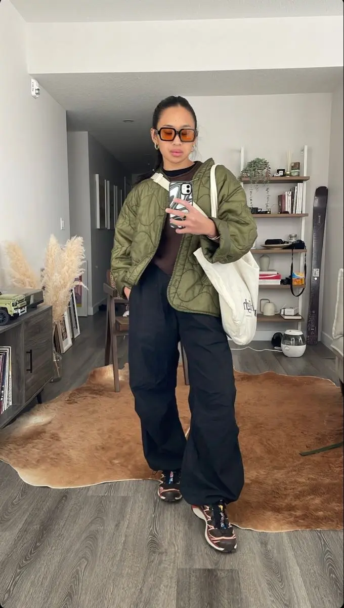 woman in olive quilted jacket brown tee black wide leg cargo pants trail sneakers with white canvas tote mirror selfie outfit 2