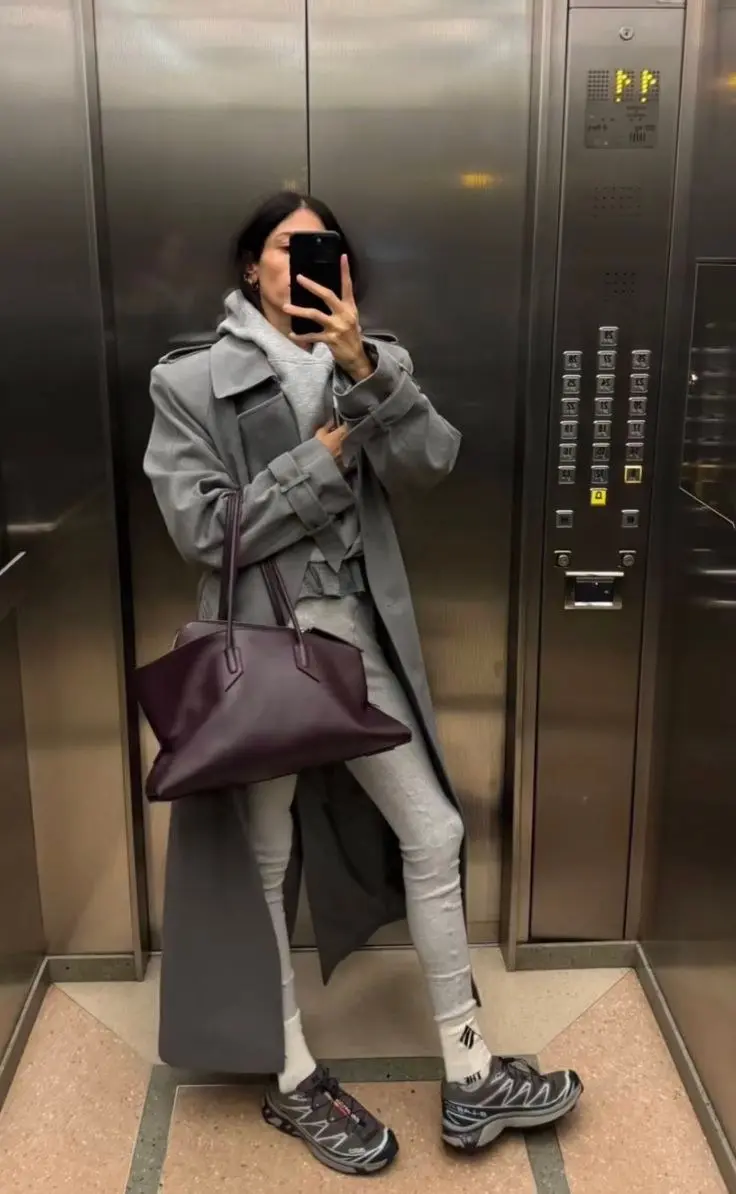 woman in grey hoodie grey sweatpants long grey trench coat burgundy leather tote trail sneakers elevator mirror selfie outfit 4