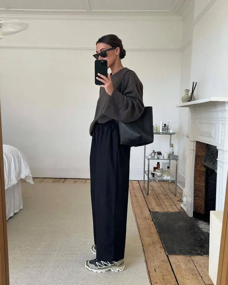 woman in brown oversized knit sweater black wide leg elastic waist trousers black leather tote cat eye sunglasses black white trail sneakers mirror selfie outfit 11