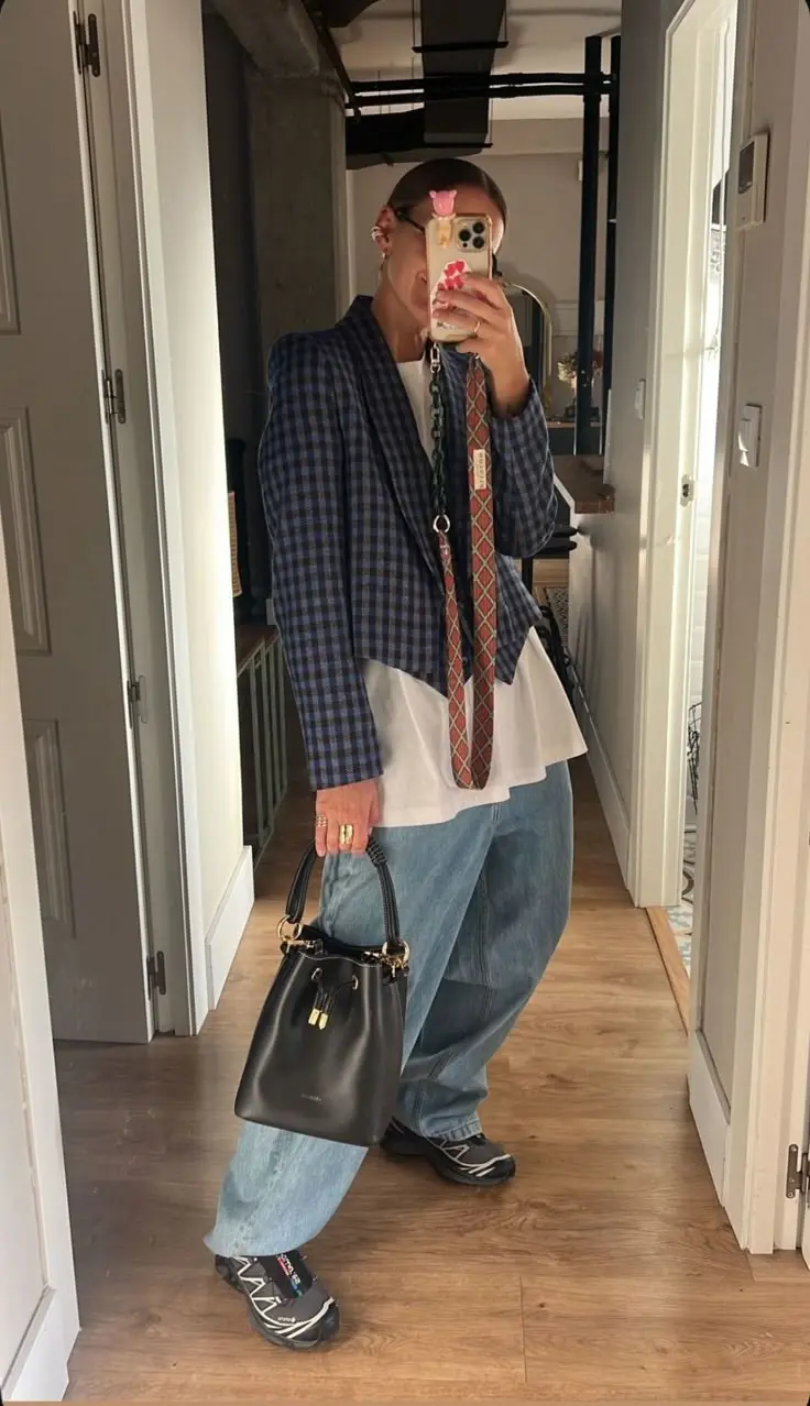 woman in navy plaid blazer white flowy tank light wash wide leg jeans black leather bucket bag patterned strap black salomon runners mirror selfie hallway outfit 18