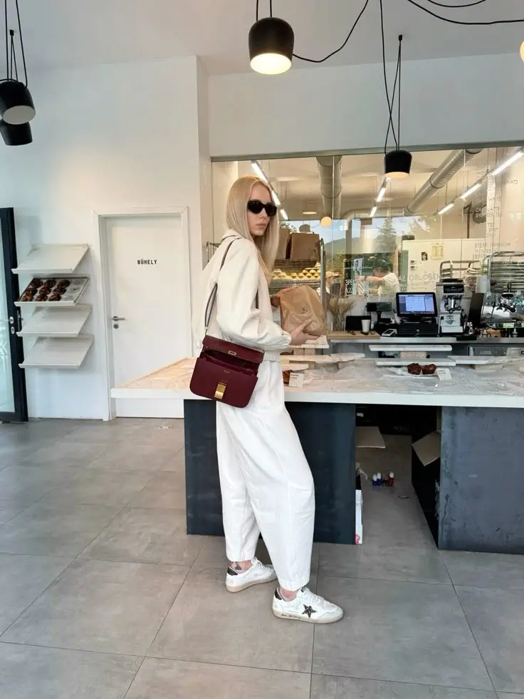 woman in all-white oversized hoodie wide trousers white distressed sneakers burgundy crossbody bag interior photo 4