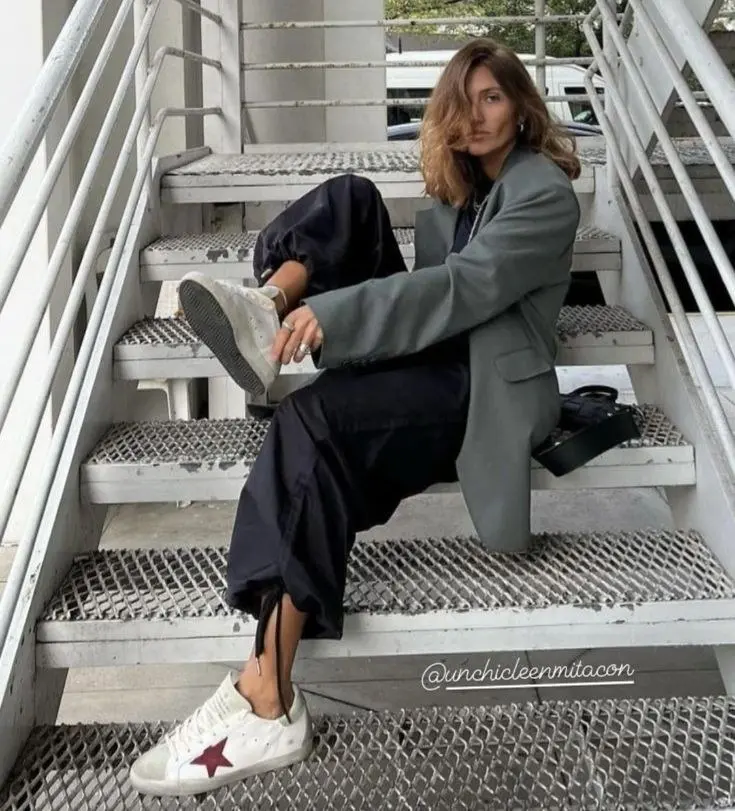 woman in oversized sage grey blazer black midi skirt side slit white distressed sneakers sitting on metal stairs photo 8