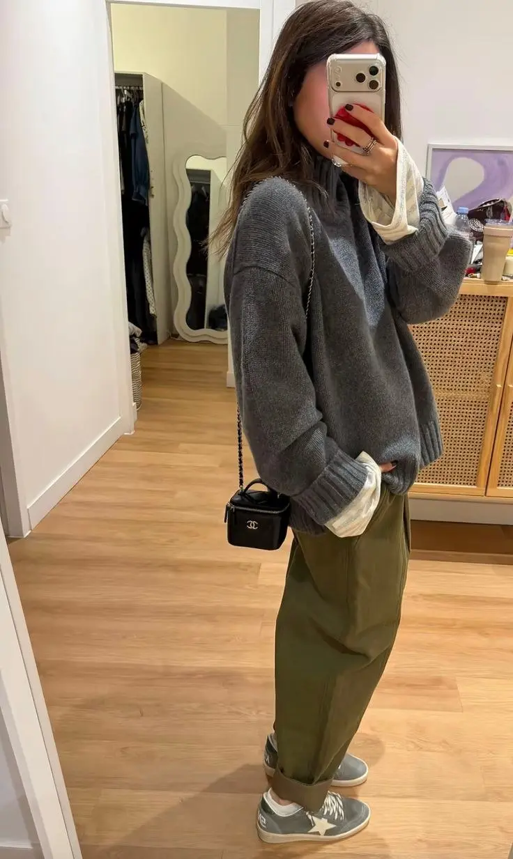 woman in oversized dark grey chunky knit sweater olive cargo trousers small black chain bag grey distressed sneakers mirror selfie photo 11