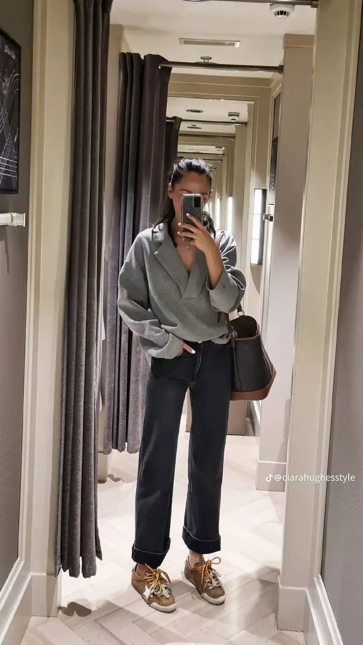 woman in grey wrap blazer sweatshirt dark cuffed wide leg jeans large brown canvas tote tan distressed sneakers mirror selfie photo 13