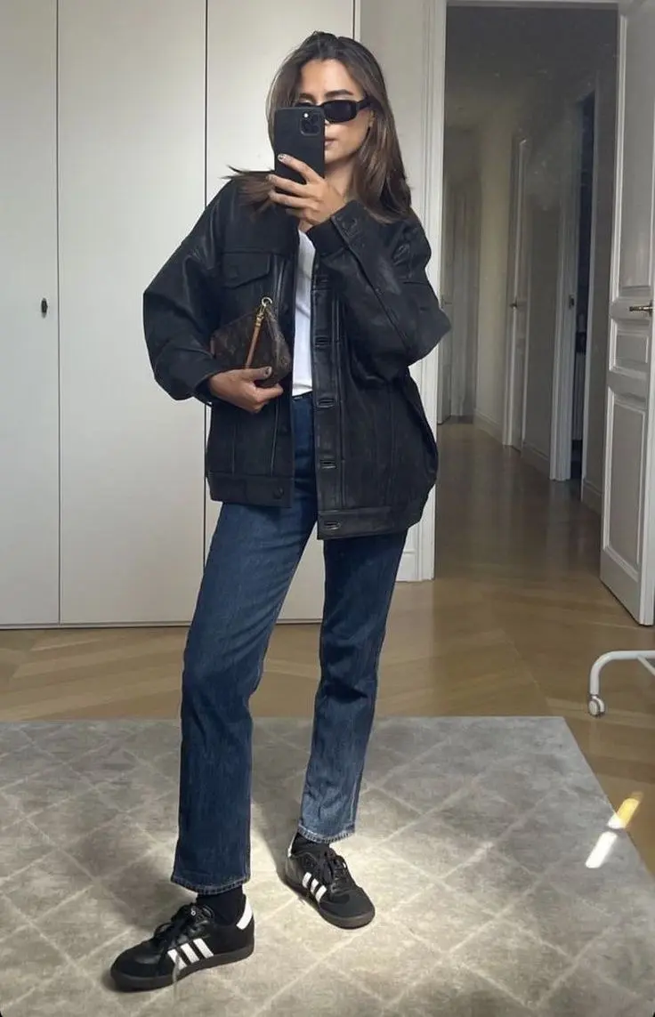 woman in oversized black leather jacket white tee dark wash straight jeans adidas samba black sneakers small monogram bag narrow sunglasses mirror selfie outfit 1