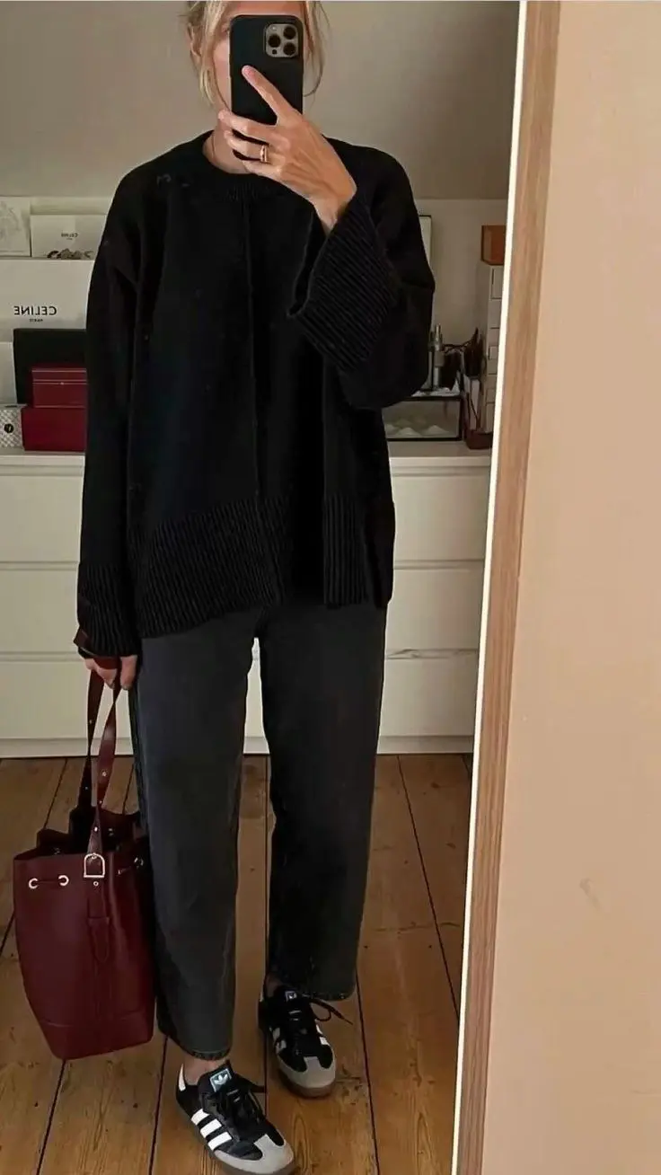 woman in black oversized double layer crewneck knit sweater grey mom jeans adidas samba black gum sole sneakers burgundy leather bucket bag with metal hardware mirror selfie indoor outfit 19