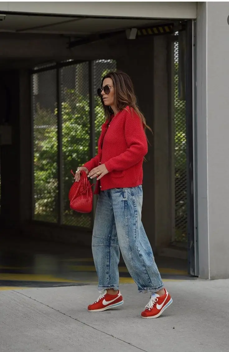 woman in red chunky knit cardigan barrel leg light wash jeans red woven bag red Nike Cortez sneakers round sunglasses street style outfit 3