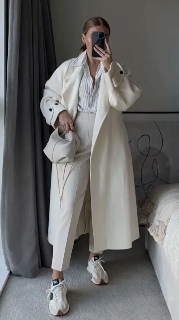 woman in ivory striped button-down shirt ivory wide-leg trousers long ivory wool coat cream New Balance sneakers ivory pouch bag mirror selfie outfit 6