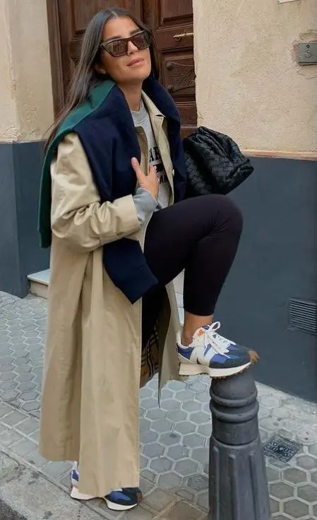 woman in camel trench coat navy jacket grey hoodie black leggings blue orange New Balance sneakers black woven bag cat-eye sunglasses outdoor outfit 14