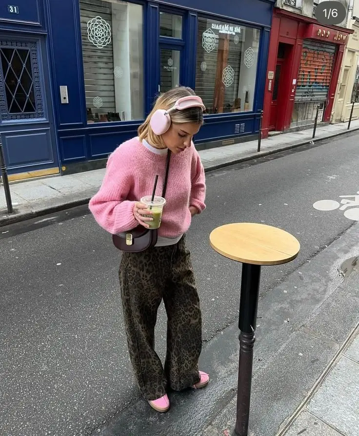 woman in pink oversized knit sweater, brown leopard wide-leg trousers, pink sneakers, small burgundy round bag, pink over-ear headphones, photo 2