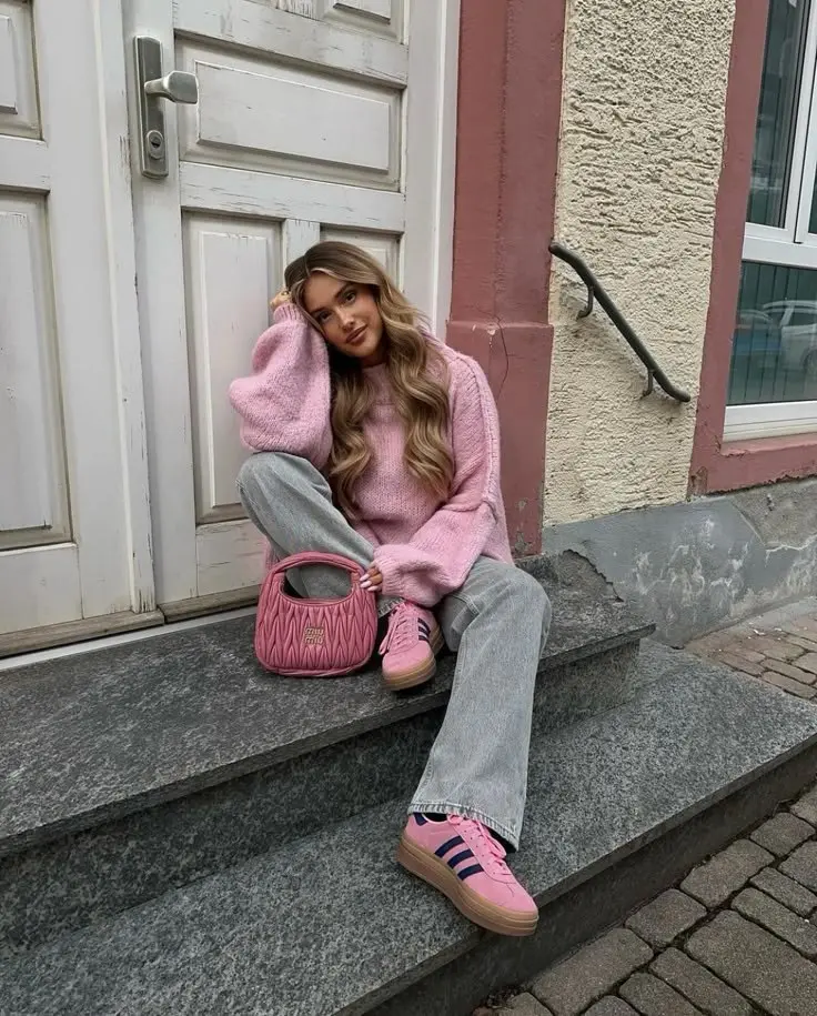 woman seated on steps in oversized pink knit sweater, light gray wide-leg jeans, pink platform sneakers, small pink quilted handbag, photo 6