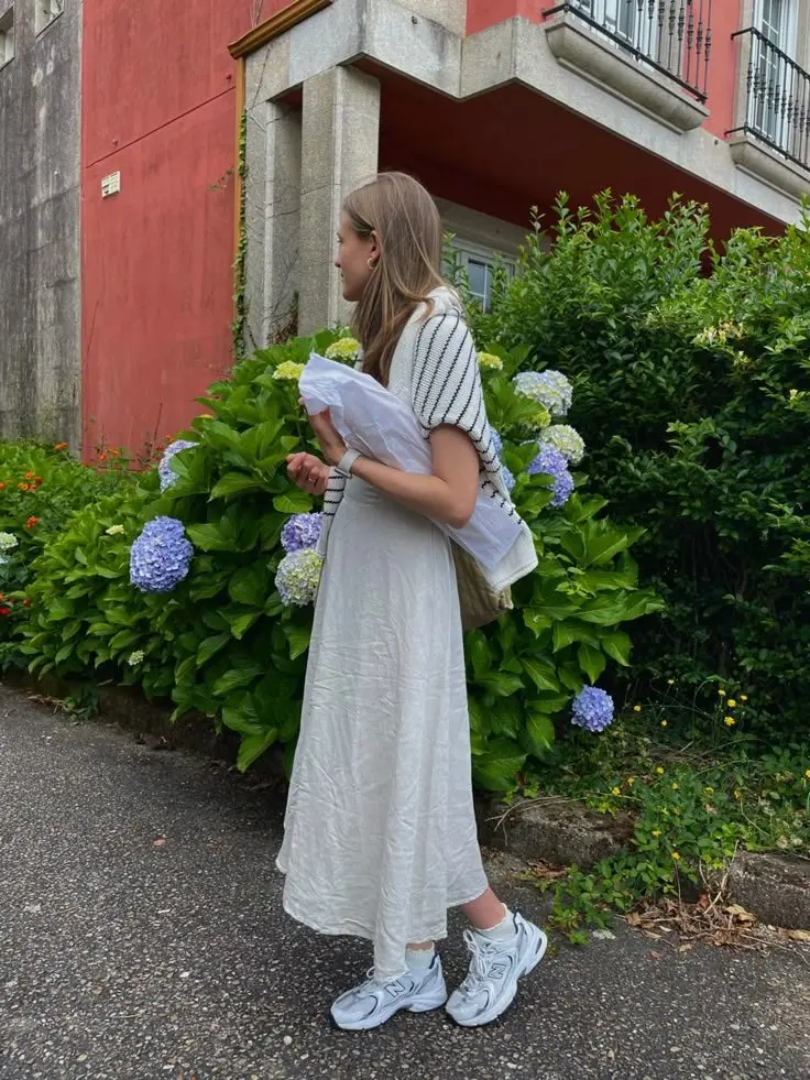 woman from behind wearing striped knit short sleeve top white crinkle midi skirt dress white crew socks New Balance 530 light blue silver sneakers floral garden outfit 11