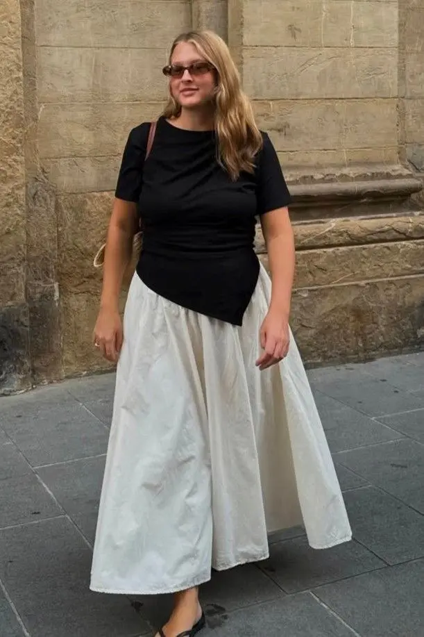 curvy blonde woman in black asymmetric hem fitted tee tucked into cream full length cotton maxi skirt flat mules and tortoiseshell sunglasses outdoors outfit 7