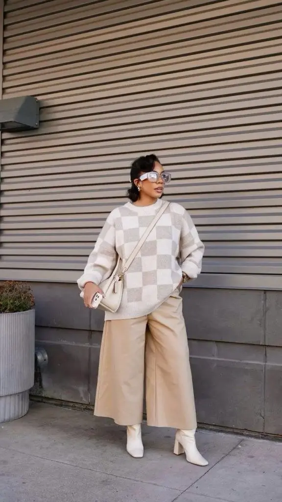 woman in cream oat checkerboard oversized sweater wide leg khaki culottes white block heel ankle boots cream crossbody shoulder bag clear frame sunglasses earrings outfit 7