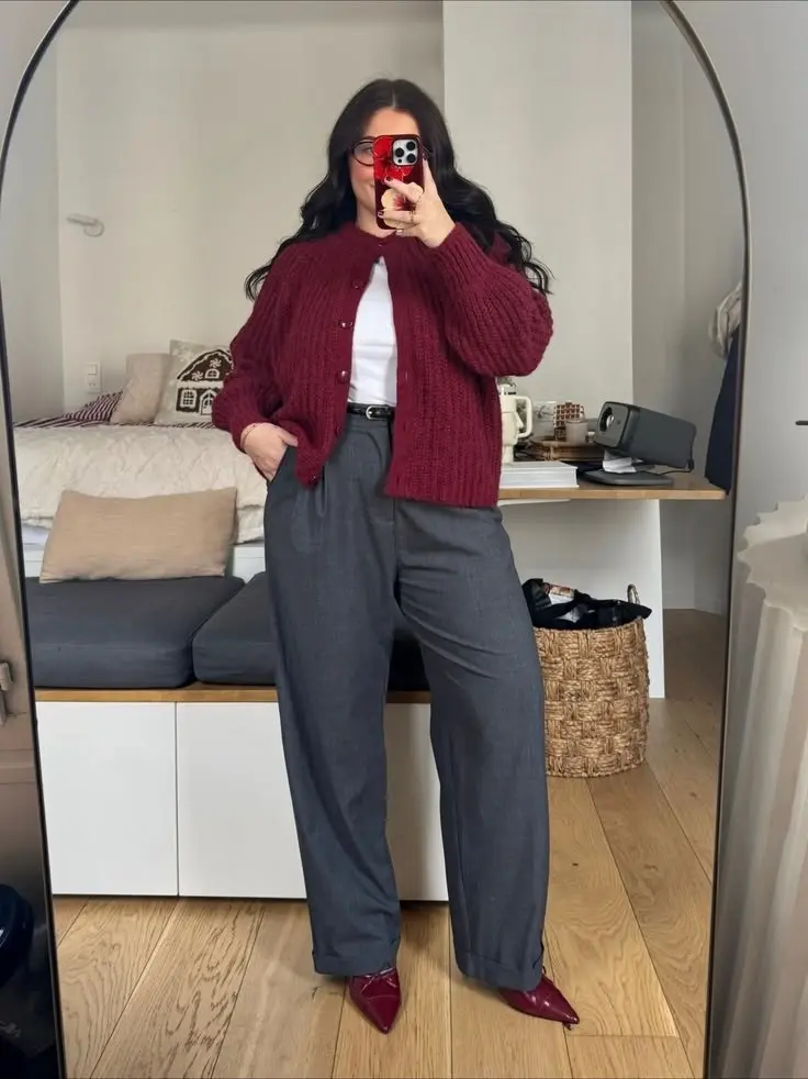 woman in deep burgundy chunky knit cardigan white fitted tee grey pleated wide leg trousers burgundy pointed patent flats thin black belt mirror selfie outfit 8