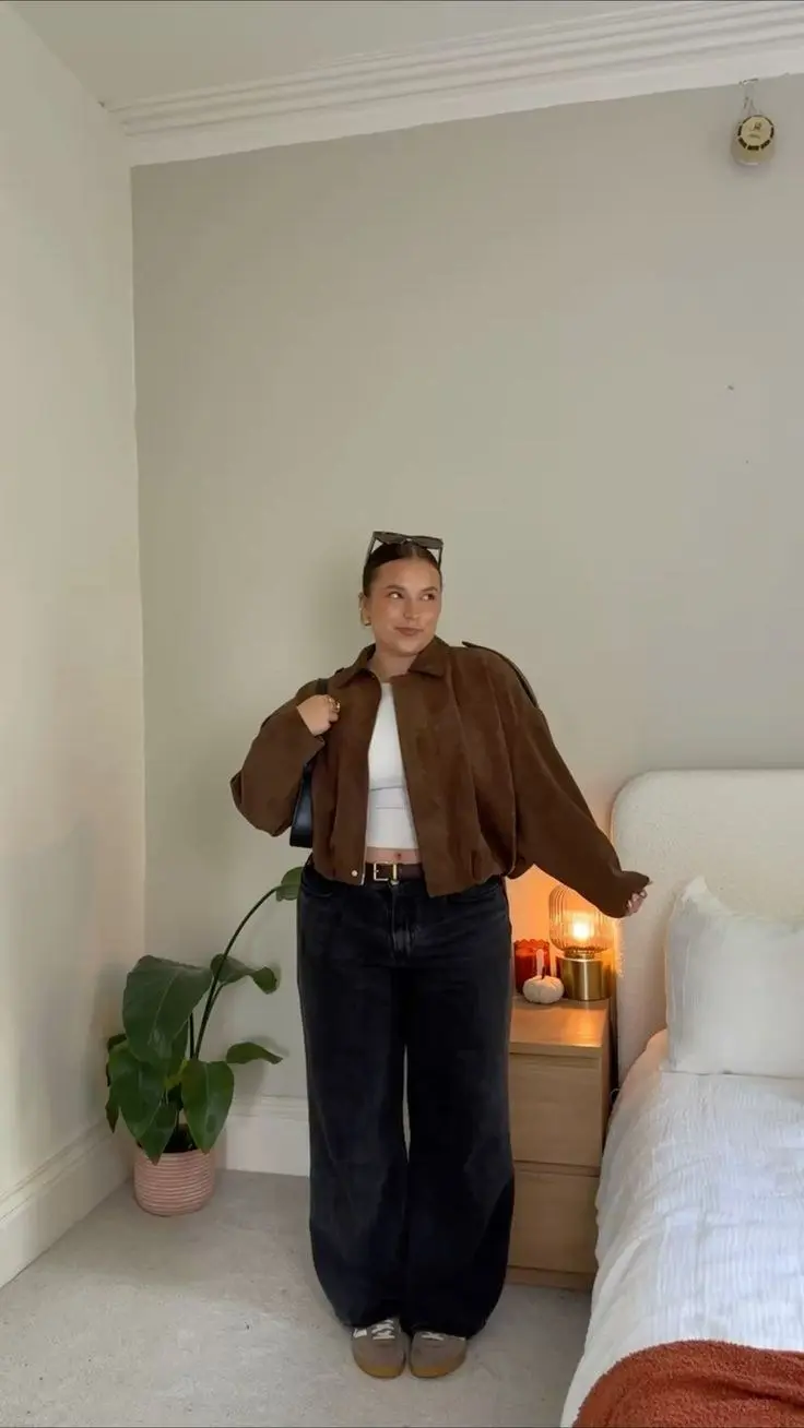 woman in brown suede cropped jacket white fitted crop top black wide leg jeans tan leather belt black shoulder bag beige grey sneakers sunglasses on head bedroom mirror selfie outfit 9