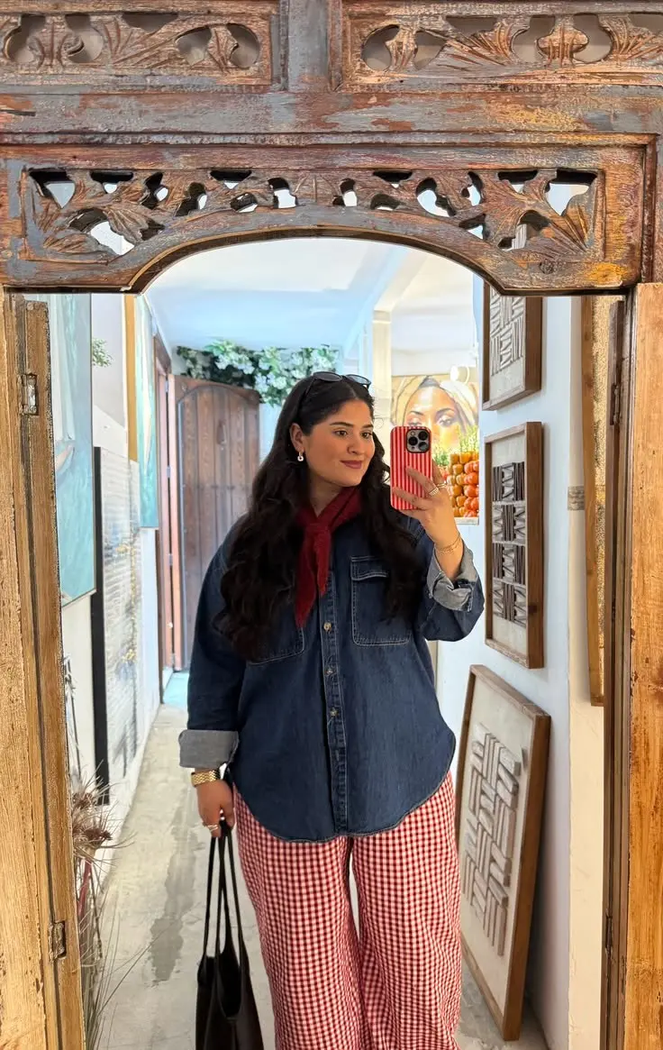 woman in oversized dark denim shirt red white gingham wide leg trousers red bandana tied at neck black tote bag gold bracelet mirror selfie ornate wooden arch frame outfit 13