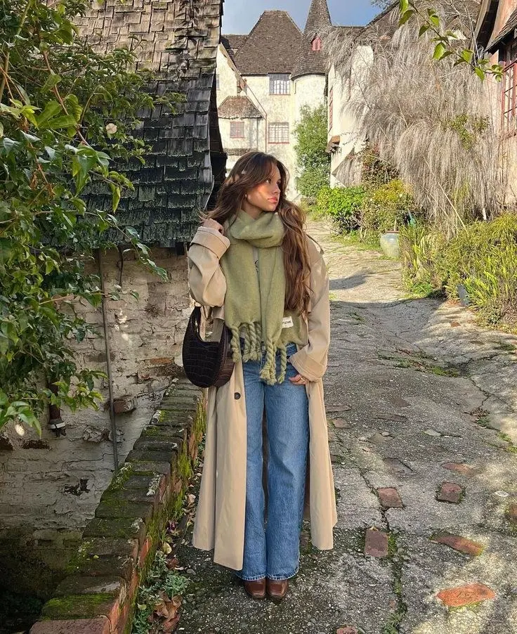 woman wearing long beige trench coat sage green oversized scarf wide leg blue jeans brown square toe boots dark croc textured bag outfit 1