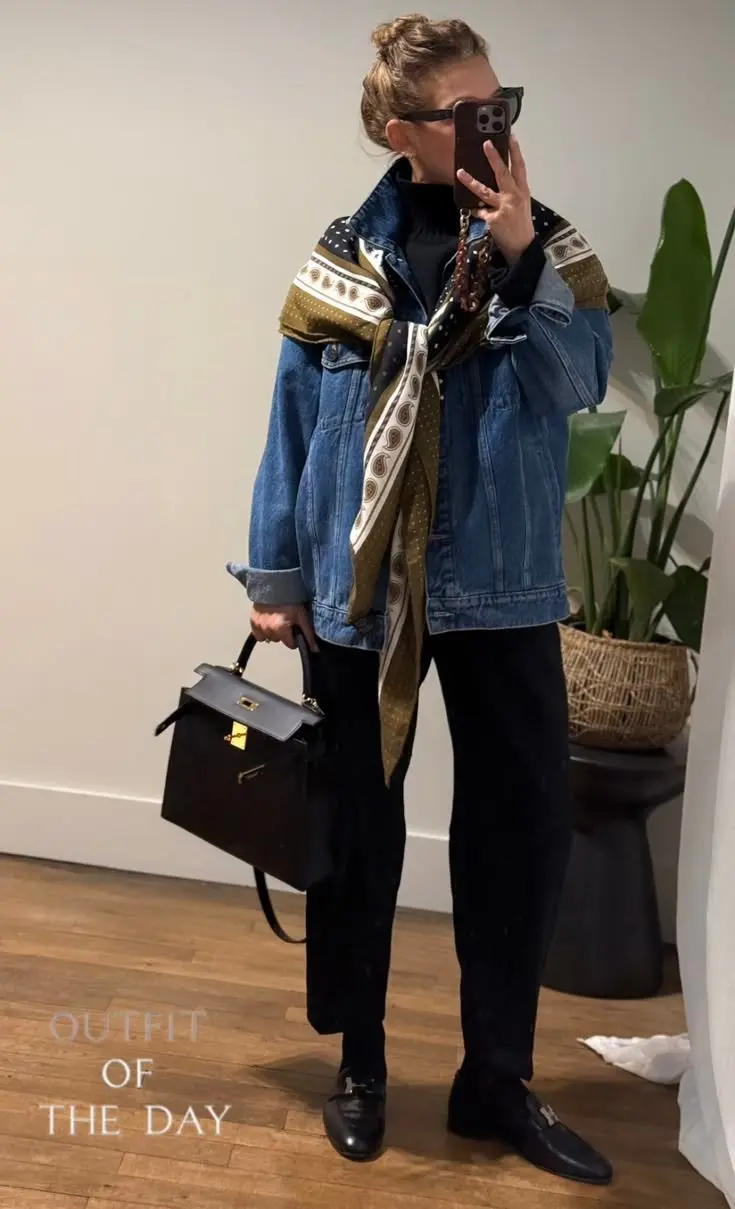 woman wearing oversized vintage wash blue denim jacket black turtleneck black wide leg trousers black bit loafers printed olive cream black silk scarf black structured top handle bag indoor plant background mirror selfie outfit 16